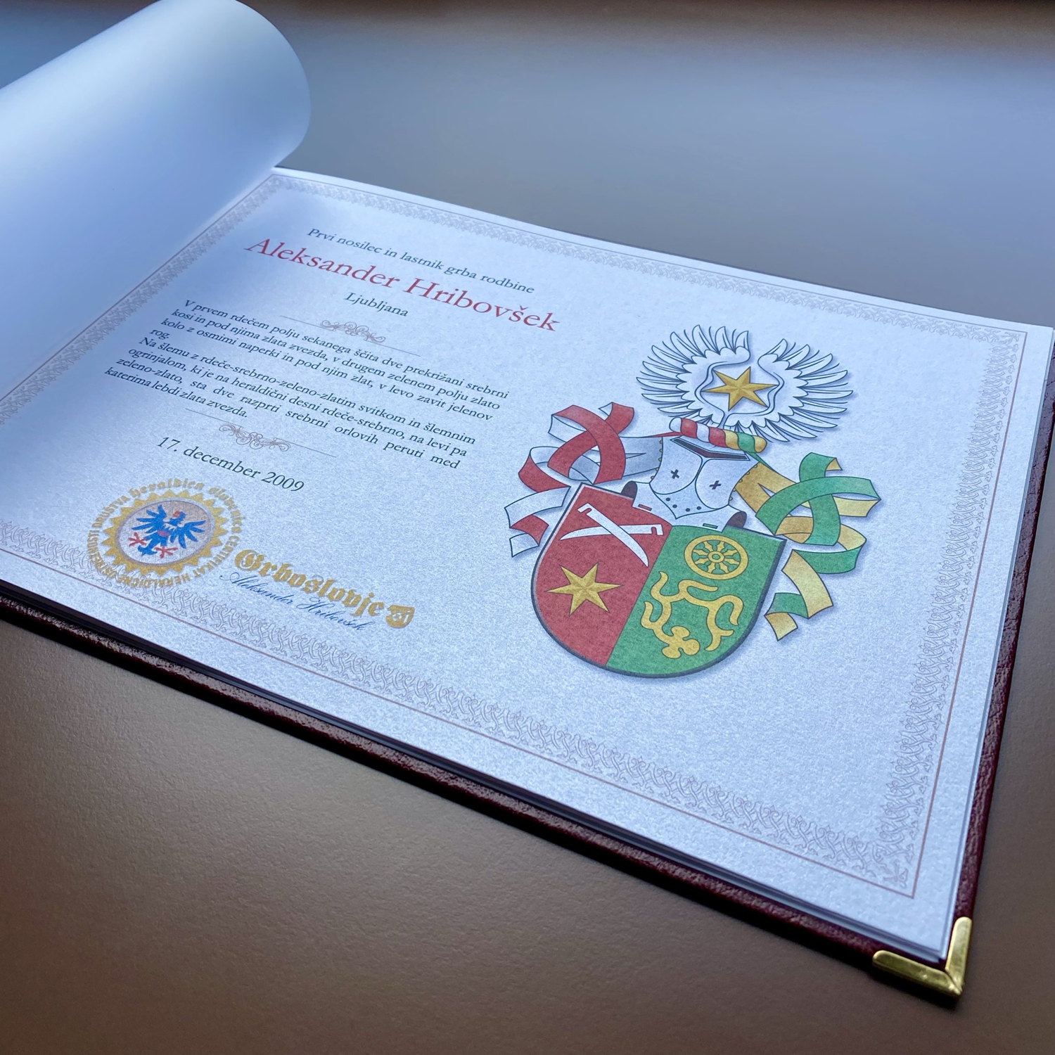 Natisnjena knjiga-grbovnica, ki vsebuje barvni grb, opis grba, barvno zastavo in opisno interpretacijo simbola. Foto: Aleksander Hribovšek, Grboslovje.si